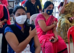 Women hold their arms after receiving the Covishield vaccine against the coronavirus at a vaccination center in Mumbai, India, July 4, 2021.