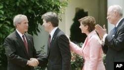 FILE - President George W. Bush shakes hands with newly sworn-in Judge on the U.S. Court of Appeals for the District of Columbia Brett Kavanaugh in the Rose Garden of the White House, June 1, 2006.