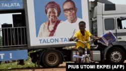 Un garçon fait du vélo en portant des tracts du président sortant Patrice Talon et de sa colistière Mariam Talata, lors d'un meeting de campagne à Abomey-Calavi, le 9 avril 2021.