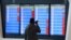 FILE - A man stands in front of a screen showing that multiple departure flights have been cancelled following the outbreak of the coronavirus, at an airport in Wuhan, Hubei province, China, Jan. 23, 2020. 