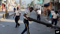 A national police officer removes a barricade in the street during a protest to demand the resignation of President Jovenel Moise, in Port-au-Prince, Haiti, Nov. 10, 2019. 