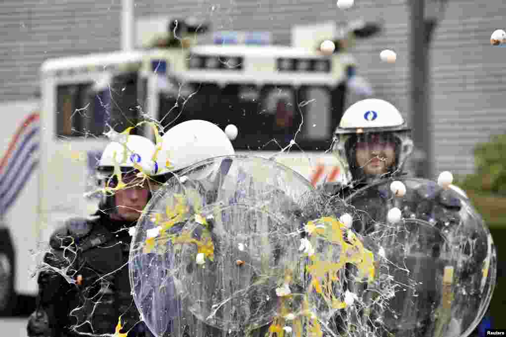 Policemen are hit by eggs as farmers and dairy farmers from all over Europe take part in a demonstration,  calling for more help with low prices and high costs, outside an emergency meeting of European Union farm ministers at the EU Council headquarters in Brussels, Belgium. 