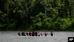 Los migrantes se toman de la mano mientras cruzan el río Tuquesa, cerca de Bajo Chiquito, Panamá, después de cruzar el Tapón del Darién desde Colombia en su camino hacia el norte hacia Estados Unidos, el sábado 9 de noviembre de 2024.