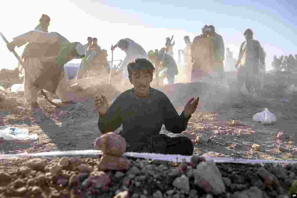 کودک افغان بر سر قبر برادرش که در اثر زلزله در ولسوالی زنده&zwnj;جان ولایت هرات جان باخته است