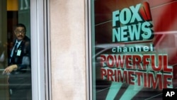 FILE - In this April 19, 2017, file photo, a security guard looks out of the the News Corp. headquarters in Midtown Manhattan. Three new lawsuits, filed May 22, allege racial discrimination or sexual harassment at Fox News, deepening the network's legal woes.