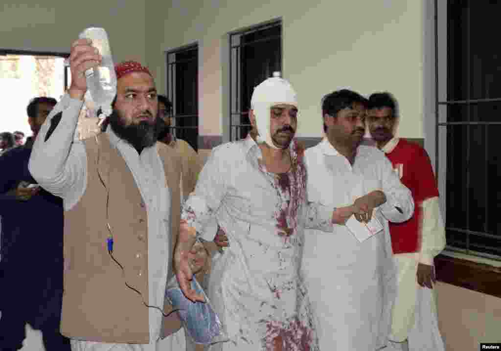 A man who was injured after an explosion in a Shi&#39;ite mosque walks with relatives after receiving medical treatment at a hospital in Shikarpur, Sindh province, Pakistan, Jan. 30, 2015.