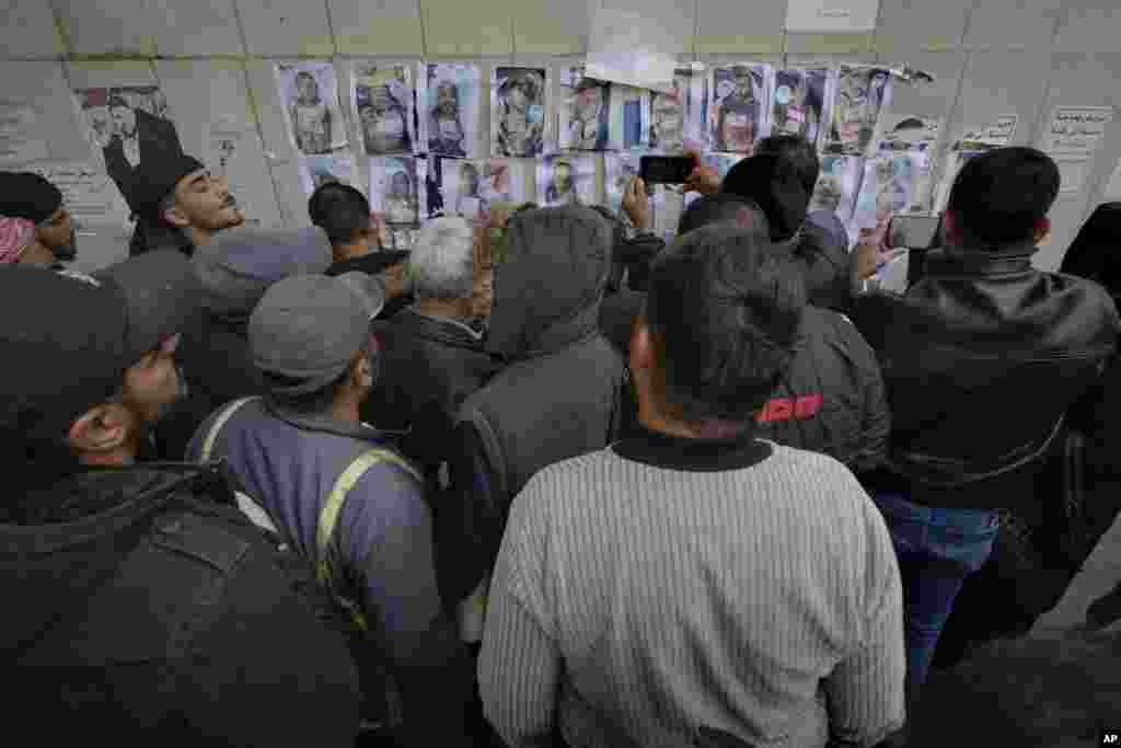 People check photos as they search for missing or deceased people on the wall outside the morgue of Al-Mojtahed Hospital in Damascus, Syria, Dec. 11, 2024.