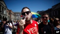 Seorang pendukung RUU pernikahan sesama jenis menunggu hasil referendum UU di depan istana Dublin, Irlandia (Foto: dok). 