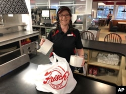 Frisch's Big Boy restaurant employee Nicole Cox bags up an order of toilet paper, an in-demand item the burger chain is now offering during the coronavirus outbreak, in Cincinnati, Ohio, March 20, 2020.