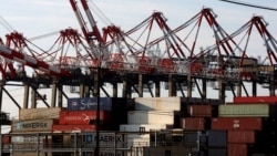 FILE - Containers are stacked beneath cranes at Port Newark Container Terminal in Newark, New Jersey. 