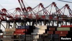 FILE - Containers are stacked beneath cranes at Port Newark Container Terminal in Newark, New Jersey. 