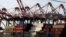FILE - Containers are stacked beneath cranes at Port Newark Container Terminal in Newark, New Jersey. 