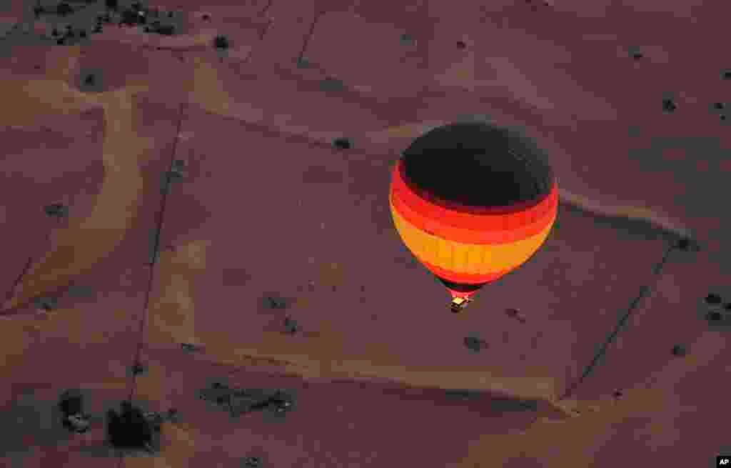 Before the sunrise, the captain of "Bar" hot air balloon ignites the flame throwers to fill up the one of the world largest balloon over a camel farm in the Margham desert about 60 kms south east of Dubai, United Arab Emirates, Oct. 21, 2014. 