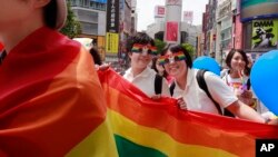 FILE - Participants smile as they march with a banner during the Tokyo Rainbow Pride parade celebrating the lesbian, gay, bisexual, and transgender (LGBT) community in Tokyo's Shibuya district, May 7, 2017.