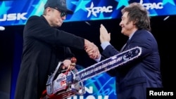 Elon Musk sostiene una motosierra y estrecha la mano del presidente de Argentina, Javier Milei, mientras asisten a la Conferencia de Acción Política Conservadora (CPAC) en National Harbor, Maryland, EEUU, el 20 de febrero de 2025. 