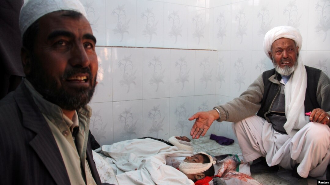 Dua anggota keluarga berduka cita atas tewasnya seorang anak dalam pertempuran di Ghazni, Afghanistan, Jumat (26/1). 