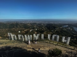 In this file photo taken on May 24, 2020 a family wearing face masks, hike at Griffith Park at the back of the Hollywood sign during the novel Coronavirus, COVID-19, pandemic in Los Angeles, California.