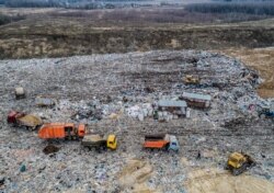 FILE - In this photo taken April 20, 2018, garbage trucks unload the trash at the Volovichi landfill near Kolomna, Russia.