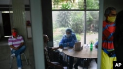 Un médico del gobierno realiza una prueba rápida gratuita de COVID-19 a un voluntario mientras otros esperan su turno en el barrio El Paraíso de Caracas, Venezuela, el jueves 14 de enero de 2021.