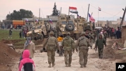 FILE - In this frame grab from video, Russians, Syrians and others gather next to an American military convoy stuck in the village of Khirbet Ammu, east of Qamishli city, Syria, Feb. 12, 2020. 