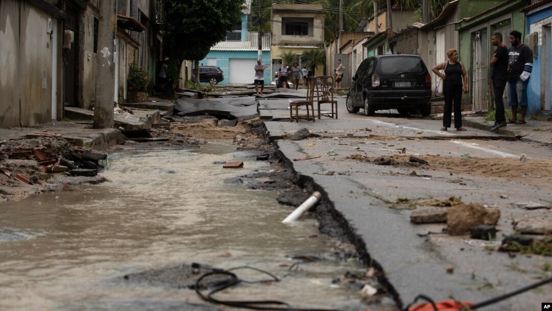 Neighbors look at the damage to a street after heavy rains caused flash floods in the Realengo neighborhood of Rio de Janeiro, Brazil, March 2, 2020. 