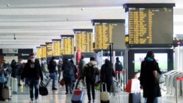 People walk carrying their luggage past train schedule displays at Termini train station, on the day the government lays out a plan of coronavirus disease (COVID-19) restrictions over the Christmas period, in Rome, Dec. 19, 2020.