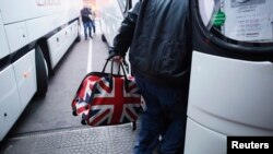 FILE - A man with a bag featuring a British Union Jack flag steps onto a bus departing from the central bus station in Sophia, Bulgaria, to London via Austria, Germany, and France, Jan 2, 2014.