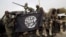 FILE - Nigerian soldiers hold up a Boko Haram flag that they had seized in the retaken town of Damasak, Nigeria, March 18, 2015. 