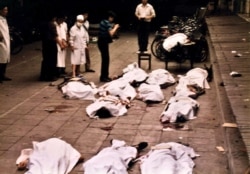 FILE - Medical workers of Beijing's Fuxingmen Hospital look at bodies of protesters killed by soldiers near Tiananmen Square on June 4, 1989.