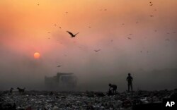 FILE - A thick blanket of smoke envelops young ragpickers searching for reusable material at a garbage dump in New Delhi, India. The government, on Wednesday, Jan. 4, 2023, approved $2.3 billion funding with an aim to grow various segments of the green hydrogen sector to abate 50 million metric tons of greenhouse gas emissions.