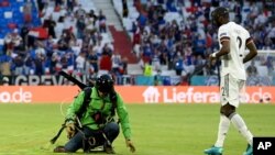 Germany's Antonio Ruediger, right, walks toward a protester who landed on the pitch before the Euro 2020 soccer championship group F match between France and Germany at the Allianz Arena stadium in Munich, June 15, 2021. 