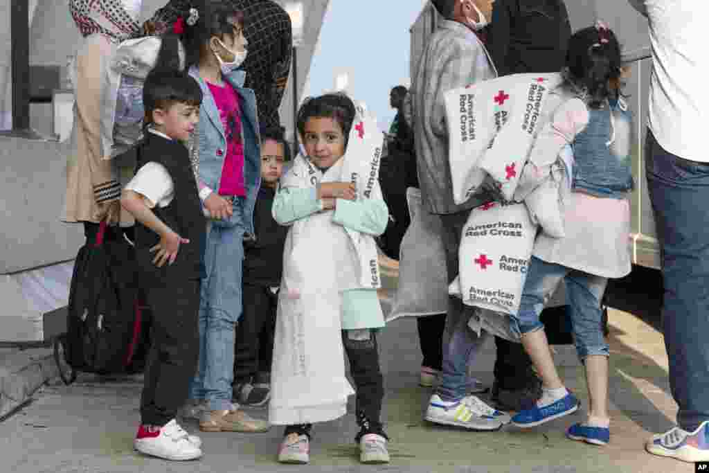 Families evacuated from Kabul, Afghanistan, wait to board a bus after they arrived at Washington Dulles International Airport, in Chantilly, Va., on Thursday, Aug. 26, 2021. (AP Photo/Jose Luis Magana)