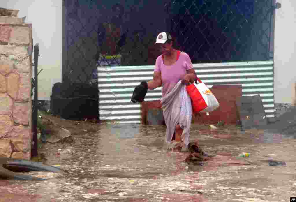 Seorang perempuan mengarungi banjir yang dibawa Badai Sandy saat ia meninggalkan rumahnya di Kingston, Jamaika (24/10).