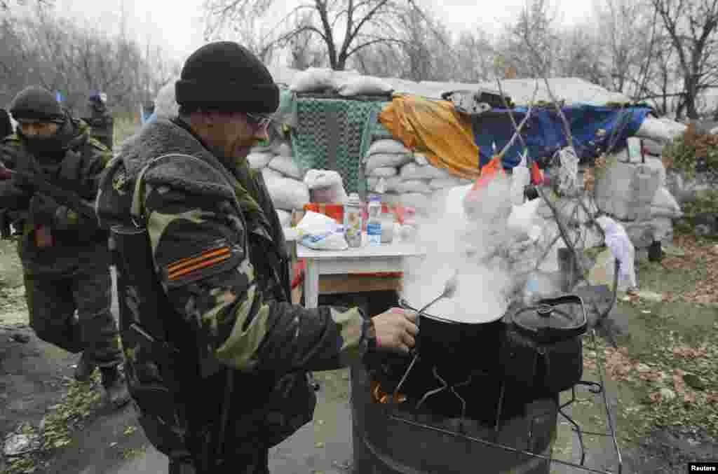 A pro-Russian separatist cooks food next to a checkpoint in the Spartak area near the Sergey Prokofiev International Airport in Donetsk, Nov. 18, 2014.