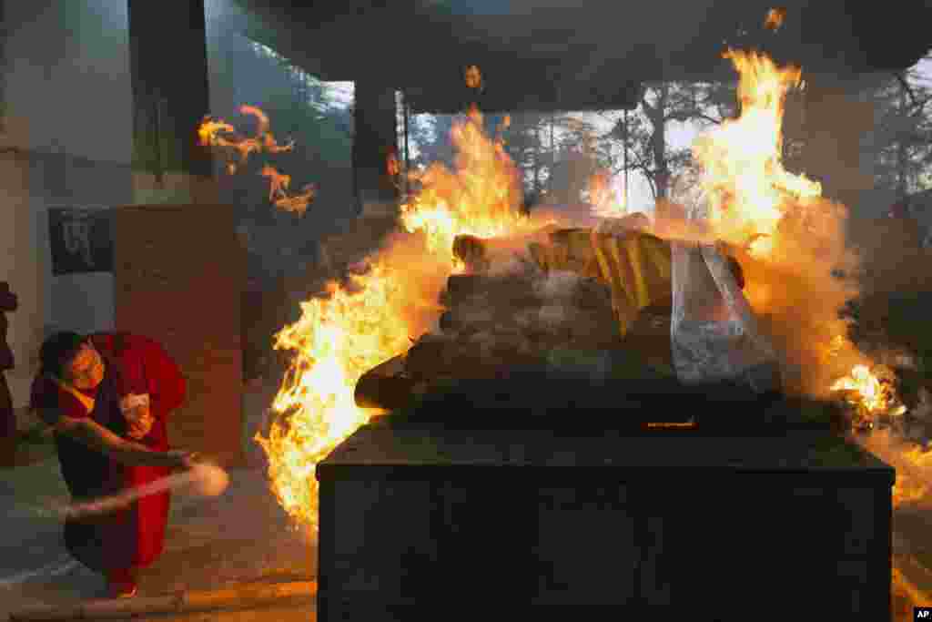 An exile Tibetan Buddhist monk throws herbs on to the funeral pyre of Palden Gyatso in Dharmsala, India, Dec. 3, 2018. Gyatso, a Tibetan Buddhist monk who spent more than 30 years in Chinese jails, died in Dharmsala on Nov. 30.