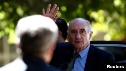 FILE - Former Argentine President Fernando de la Rua waves in front of a policeman as he arrives to a courtroom in Buenos Aires, Dec. 23, 2013.