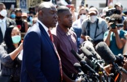 Quincy Mason, right, a son of George Floyd, listens, June 3, 2020, as family attorney Ben Crump, left, addresses a news conference as they and some Floyd family members visited a memorial in Minneapolis where Floyd was arrested on May 25.