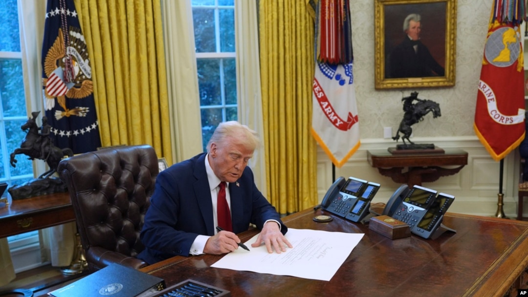 FILE - US President Donald Trump signs executive orders in the Oval Office at the White House, Jan. 30, 2025, in Washington.