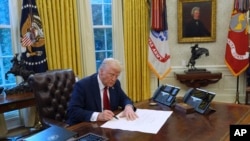 FILE - US President Donald Trump signs executive orders in the Oval Office at the White House, Jan. 30, 2025, in Washington.