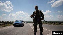 An armed pro-Russian separatist stands guard at a road check point outside the eastern Ukrainian city of Luhansk, June 8, 2014. 