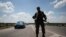An armed pro-Russian separatist stands guard at a road check point outside the eastern Ukrainian city of Luhansk, June 8, 2014. 