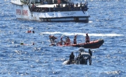 Migrants swim after jumping off the Spanish rescue ship Open Arms, close to the Italian shore in Lampedusa, Italy, Aug. 20, 2019.