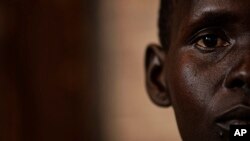 FILE - a South Sudanese refugee and 32-year-old mother, who was raped for several days by a group of soldiers before she was allowed to leave, stands by a window at a women's center.