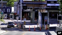 A vehicle in Canada waits for a gate to rise while crossing into Derby Line, Vermont from Stanstead, Quebec, July 11, 2018. 