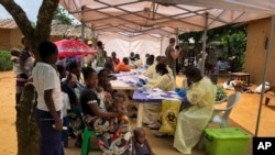 A woman and her children wait to receive Ebola vaccinations, in the village of Mabalako, in eastern Congo Monday, June 17, 2019.