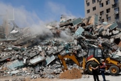 Workers clear the rubble of a building that housed the offices of the The Associated Press and broadcaster Al-Jazeera, in Gaza City May 16, 2021.
