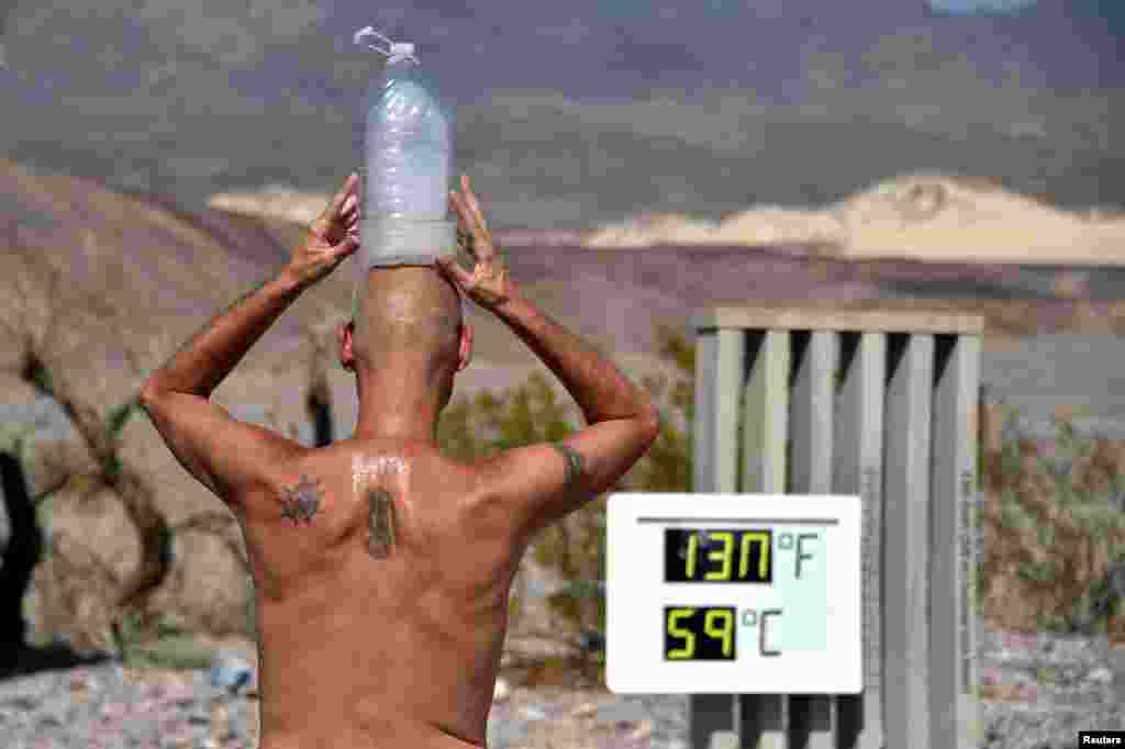 Steve Krofchik of Las Vegas keeps cool with a bottle of ice on his head as the unofficial thermometer reads 130° F (54.4° C) at the Furnace Creek Visitors Center in Death Valley, California, Aug. 17, 2020.