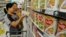 A sales assistant helps a customer to select Dumex milk powder at a market in Hefei, China, August 5, 2013. 