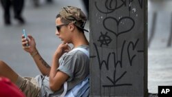 FILE - A young man checks his cell phone in Sao Paulo, Brazil, Dec. 17, 2015. A judicial order issued earlier this week left 100 million Brazilians without access to the popular WhatsApp messaging platform for 72 hours.