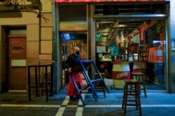 FILE - A worker wearing a face mask to prevent the spread of coronavirus prepares to close a bar at 10 p.m. due to new measures against COVID-19, in Pamplona, northern Spain, Oct. 17, 2020. (AP)